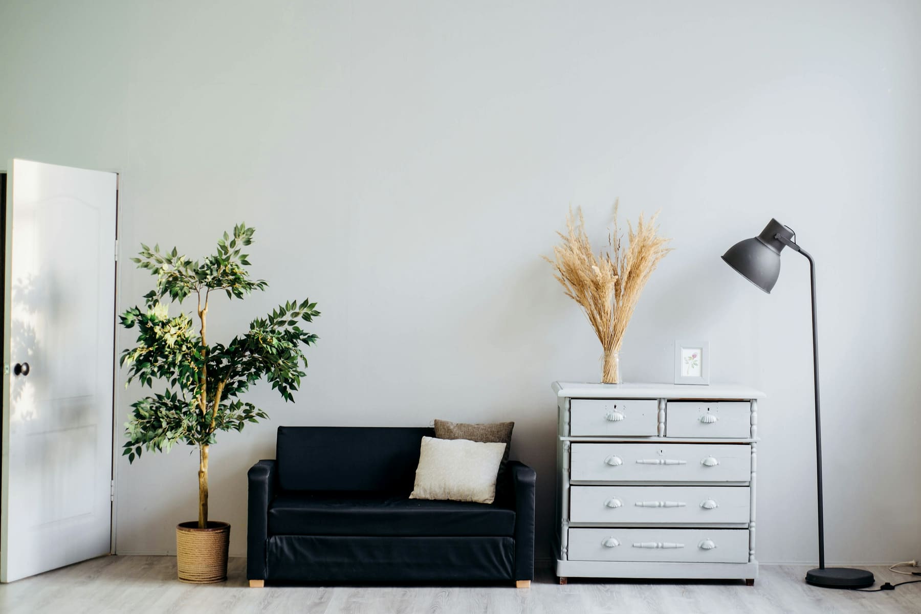 Ruhiger Wohnraum mit weissen Wänden, Sofa und Kommode