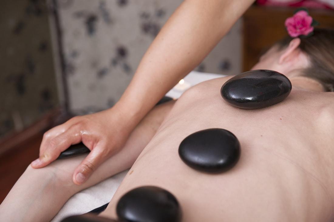 Sportmassage mit warmen Steinen entlang der Wirbelsäule