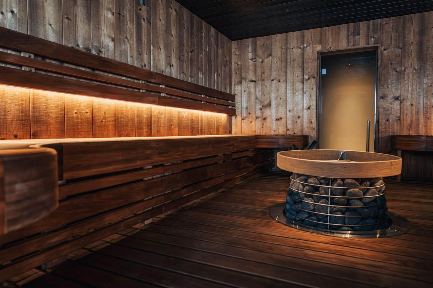Sauna aus dunklem Holz mit warmem, indirektem Licht